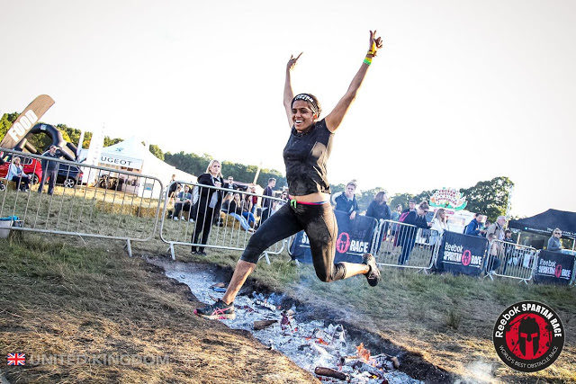 indian woman covered in mud jumping across a fire
